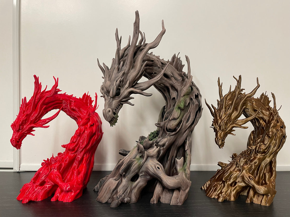 Three Driftwood Dragons printed in different colours side by side