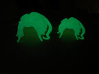 Two Skull Hideaways photographed in a dark room, the prints glowing green